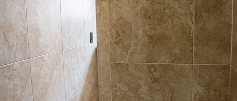 A bathroom with beige tiles, a white toilet, and a paper towel dispenser.