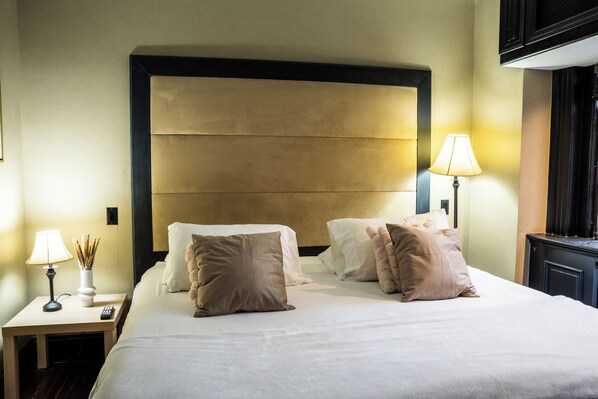 Una habitación de hotel con una cama grande, dos mesitas de noche, una lámpara y un espejo.