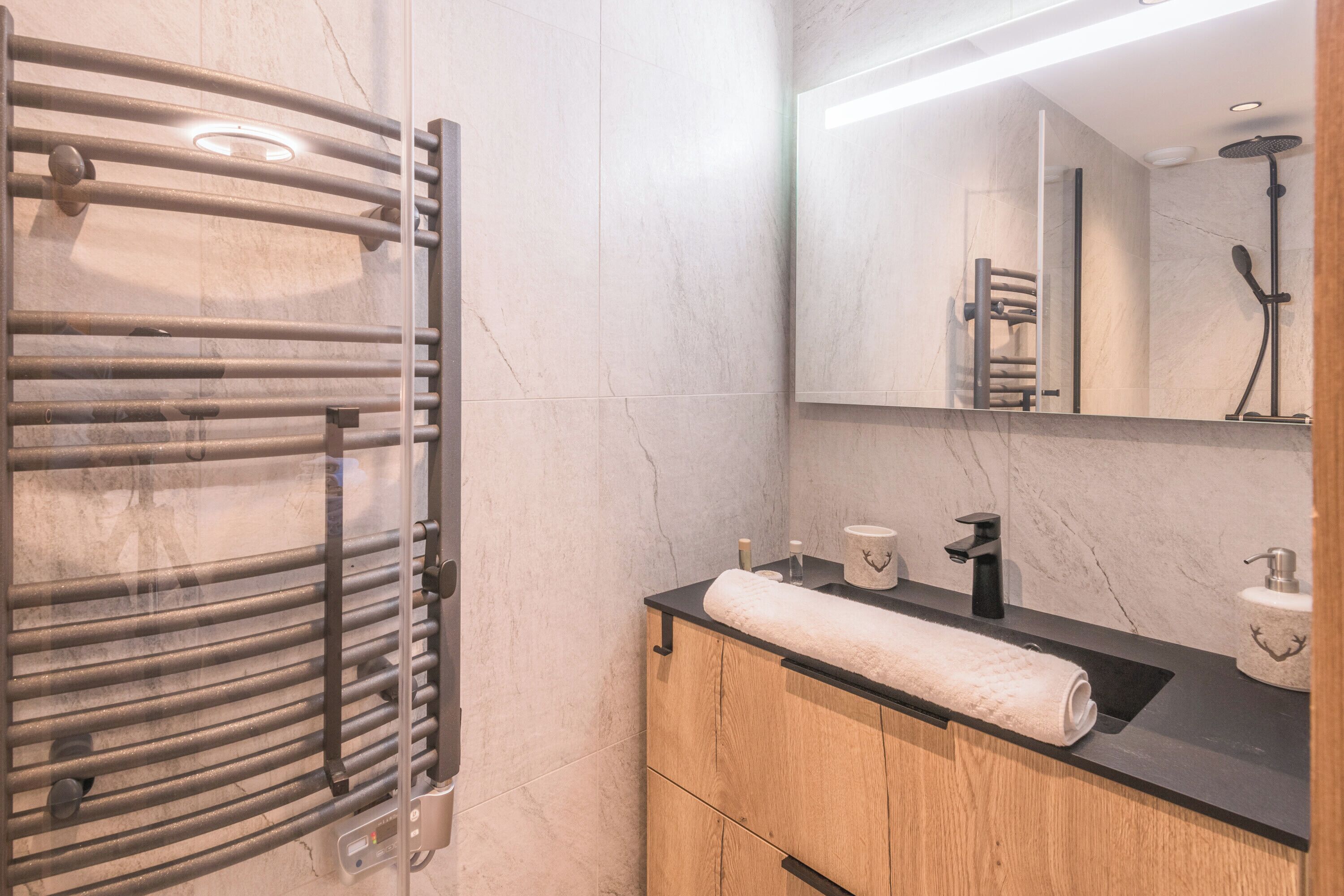 Un baño moderno con un perchero, un lavabo con encimera negra y un espejo sobre el lavabo.