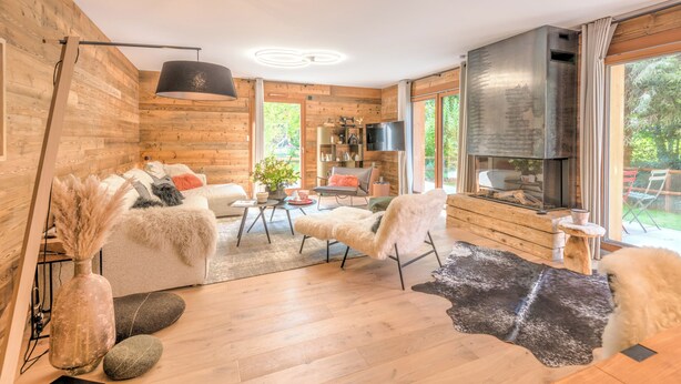 Un salon moderne avec des murs en bois, une cheminée, un canapé, une table basse et un téléviseur.