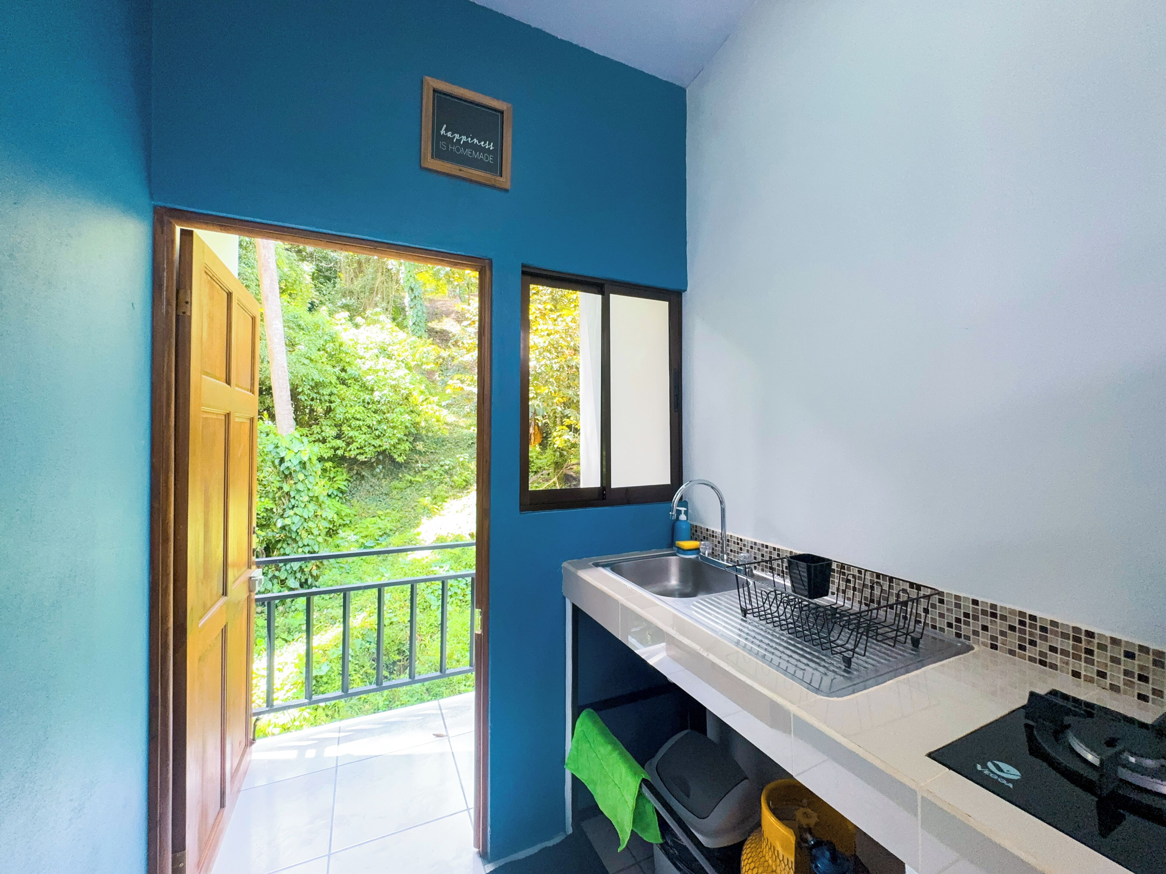Une cuisine équipée d’un évier, d’une fenêtre et d’une porte donnant sur un balcon.