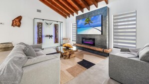 A modern living room with a large flat-screen TV, a wooden ceiling, a sofa, and a coffee table. - Exclusive Ranch • Lake Access • Courts & Pool_BBQ (Miami)