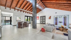 A spacious living area with a high ceiling, a kitchen, and a seating area with a glass table and sofa. - Exclusive Ranch • Lake Access • Courts & Pool_BBQ (Miami)