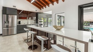 A modern kitchen with a large island, stainless steel appliances, and a wooden ceiling. - Exclusive Ranch • Lake Access • Courts & Pool_BBQ (Miami)