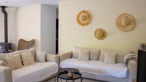 A living room with a sofa, a small round table, and two wall-mounted hats. - Casa Isabella Di Santa Lucia (Zonza)