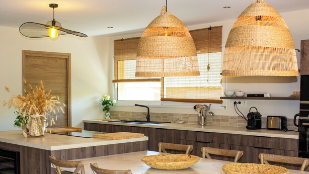 A modern kitchen with a central island, wooden chairs, and woven pendant lights. - Casa Isabella Di Santa Lucia (Zonza)