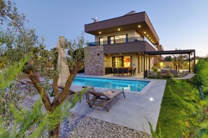 A modern two-story house with a swimming pool, outdoor seating, and a stone wall. - Villa Bavigo by Istrabook (Marcana)