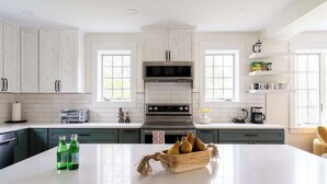 Une cuisine moderne avec des meubles blancs, un îlot central et un four encastré.