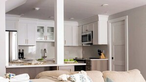 Quarto de hotel moderno com cozinha compacta, sofá e área de refeições, incluindo toalhas.