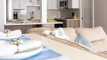 Una habitación de hotel moderna con kitchenette, sofá y comedor, además de toallas.