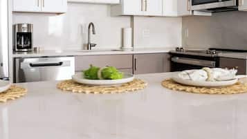 A modern kitchen with white cabinets, a stainless steel refrigerator, a coffee maker, and a microwave.