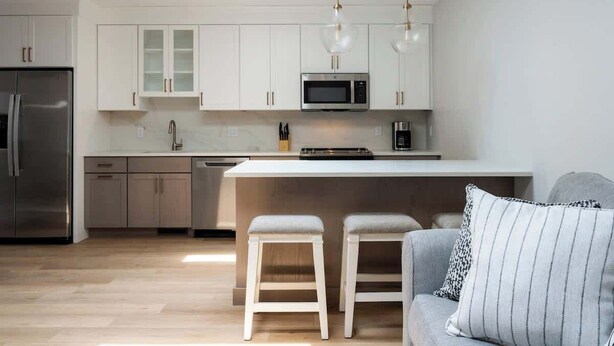A modern kitchen with white cabinets, stainless steel appliances, and a central island with stools.