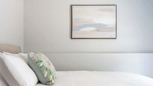 A neatly made bed with white bedding and a single decorative pillow.