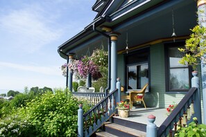 A porch with a staircase, wicker chairs, and hanging flower baskets.