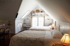A cozy attic bedroom with two beds, a wooden chair, and a desk. - Harbor Hill House Bayfield, WI (Bayfield)