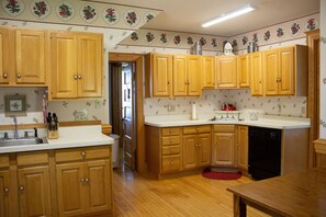 A kitchen with wooden cabinets, a sink, and a dishwasher. - Harbor Hill House Bayfield, WI (Bayfield)
