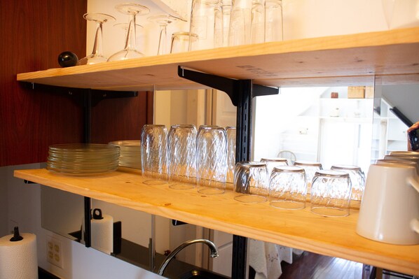 A kitchen with wooden shelves holding glassware and plates.