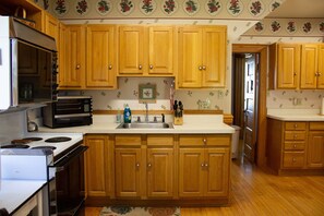 Una cocina con armarios de madera, estufa, microondas y pileta.