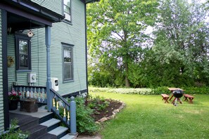 A house with a porch, steps, and a garden with a grill and benches. - Harbor Hill House Bayfield, WI (Bayfield)