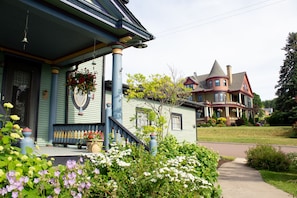 A two-story house with a porch, a front yard with flowers, and a driveway. - Harbor Hill House Bayfield, WI (Bayfield)