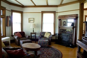 A traditional living room with a fireplace, patterned furniture, and a large window. - Harbor Hill House Bayfield, WI (Bayfield)