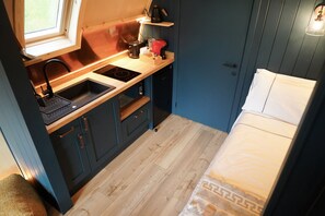 A compact kitchenette with a sink, stove, and storage cabinets.