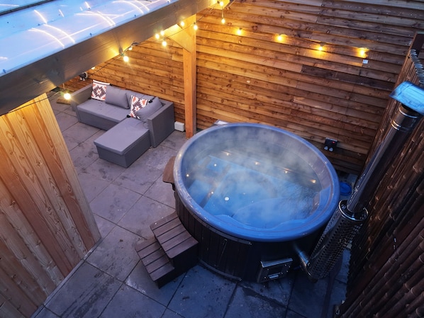 A hot tub with a wooden deck and outdoor seating area.