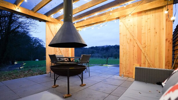 An outdoor patio with a fire pit, seating, and string lights. - Luxury Rural Cabin with Wood Fired Hot Tub (Canonbie)