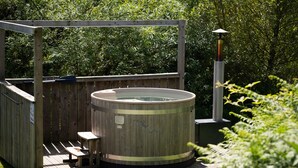 A wooden hot tub with a bench, surrounded by a wooden deck and a pergola. - Cosy Rural Cabin With Hot Tub (Pwllheli)