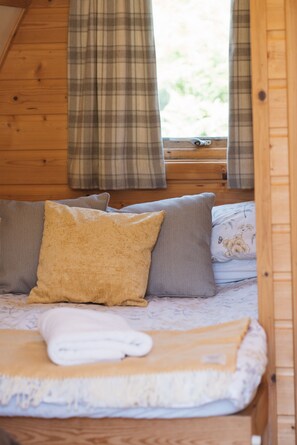 Ein gemütliches Zimmer mit einem Bett, Kissen und einem fenster mit Vorhängen.