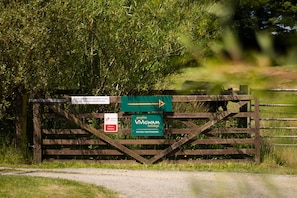 A wooden gate with directional signs and a 'Gwyliau WIGWAM holidays' sign.