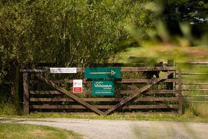 A wooden gate with directional signs and a 'Gwyliau WIGWAM holidays' sign.