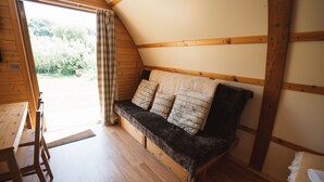 Una habitació acollidora amb una banca de fusta, una taula petita i una porta que dona a una zona exterior.