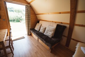 A cozy room with a wooden bench, a small table, and a door leading to an outdoor area.