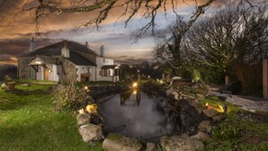 A stone house with a pond, surrounded by trees and a cloudy sky. - Worvas Counthouse -  Country Cottage - Hot Tub - Pet Friendly (St Ives)