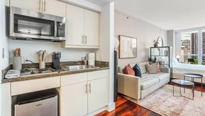 A modern kitchen with stainless steel appliances, a built-in microwave, and a dishwasher. There is a dining area with a sofa and a small table. - Coconut Grove Studio: Sleeps 4 Includes Parking (Miami)