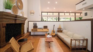 A spacious living room with a fireplace, a sofa, a coffee table, and a guitar.
