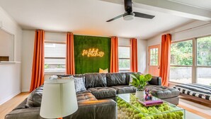 Un salon moderne avec un canapé en cuir, une table basse en verre et des rideaux orange.