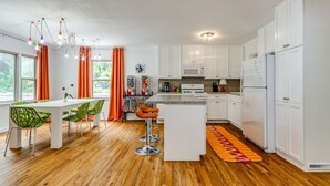 Une cuisine moderne avec des meubles blancs, un plancher en bois et un îlot central doté de tabourets de bar.