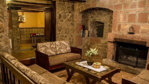 Una sala acogedora con una chimenea de piedra, un sofá, una mesa de centro con una planta y una estantería.
