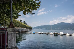 A calm lake with boats docked, a stone bridge, and a tree-lined path. - Apartment 'Blue Water' with Air Conditioning (Porto Valtravaglia)