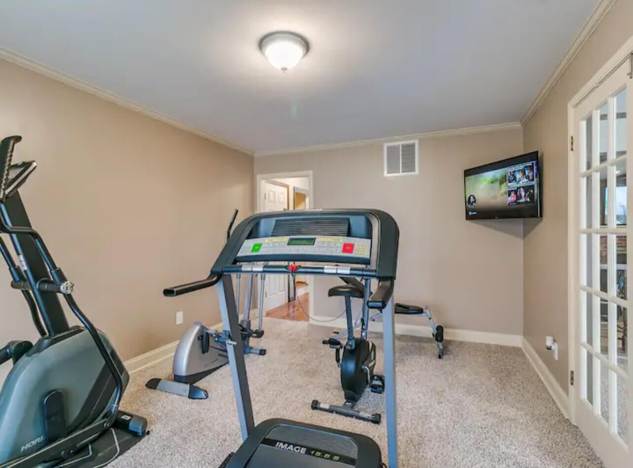 Una palestra in casa con due tapis roulant, una cyclette e un televisore montato a parete.