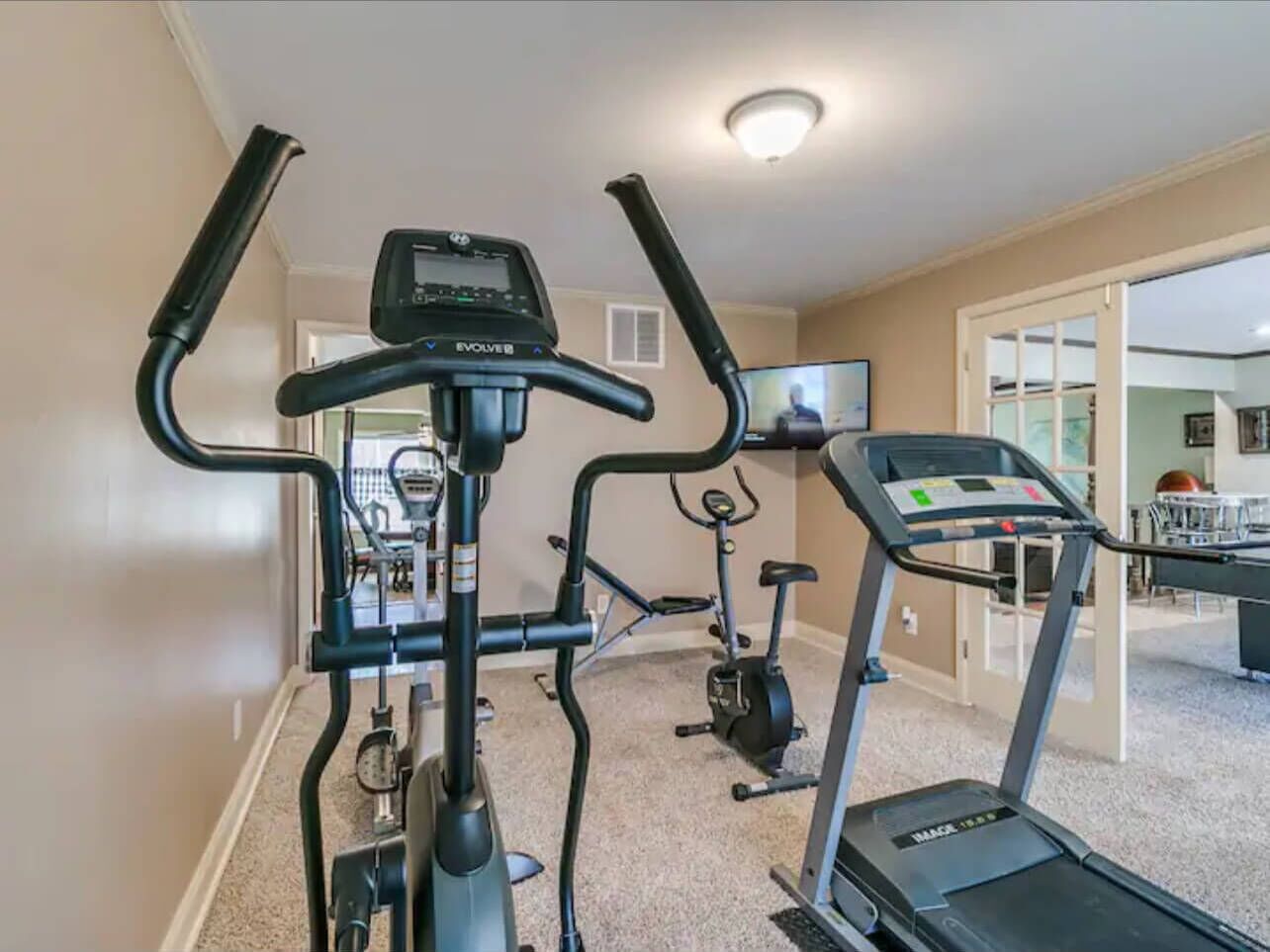 Un gimnasio en casa con cinta de correr, elíptica y bicicleta estática.