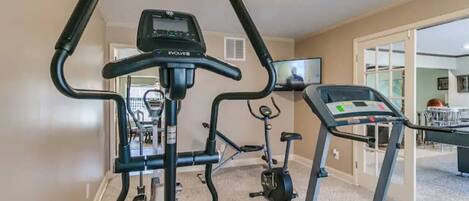 Un gimnasio en casa con cinta de correr, elíptica y bicicleta estática.