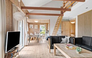 A modern interior with a wooden staircase, a dining area, and a living space with a sofa and coffee table. - Beautiful home in Hejls with sauna (Hejls)
