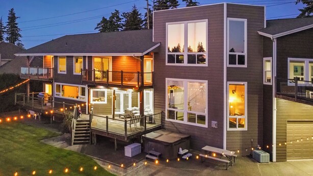 A modern two-story house with a covered patio, large windows, and a garage.