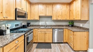 A kitchen with wooden cabinets, granite countertops, stainless steel appliances, and a dishwasher.