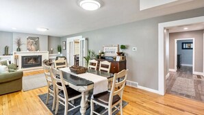 A modern living room with a fireplace, dining area, and a hallway leading to another room.