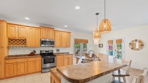 Una cocina moderna con armarios de madera, encimeras de granito, electrodomésticos de acero inoxidable y una isla grande con asientos.