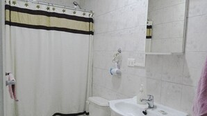 Baño con inodoro, lavamanos y cortina de ducha.